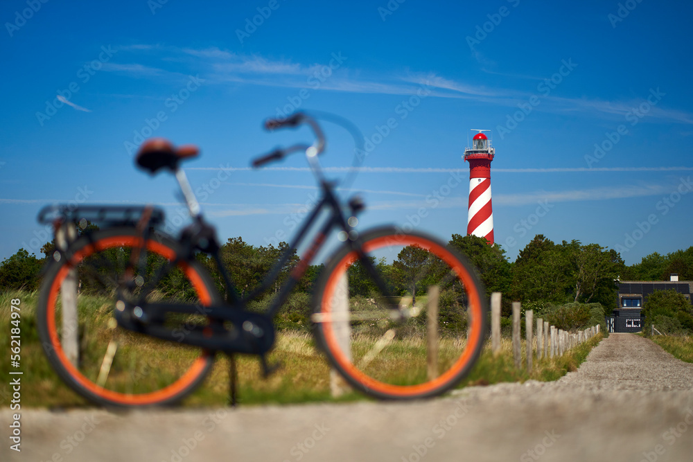 Dutch lighthouse on the horizon. Ladies bike out of focus. Landscape on bright sunny summer afternoon. Holland, Zeeland, Haamstede.