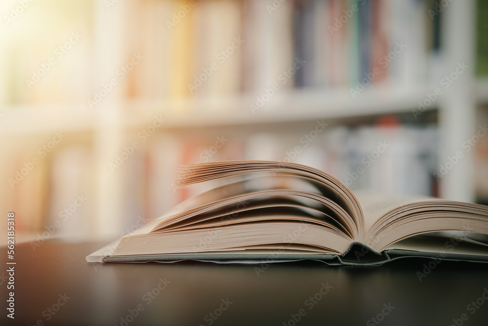 Open book on a black table. Library in the background. Book on table close up.
