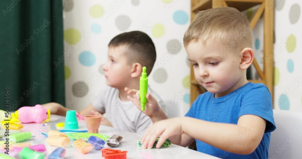 Cute children sitting at the table and plays with playdough Cute children sitting at the table and plays with playdough