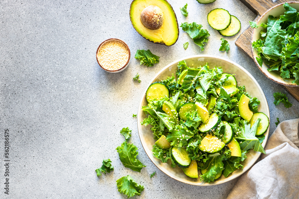 Green salad, vegan meal. Kale salad leaves with cucumber and avocado. Top view. Green salad, vegan meal. Kale salad leaves with cucumber and avocado. Top view.