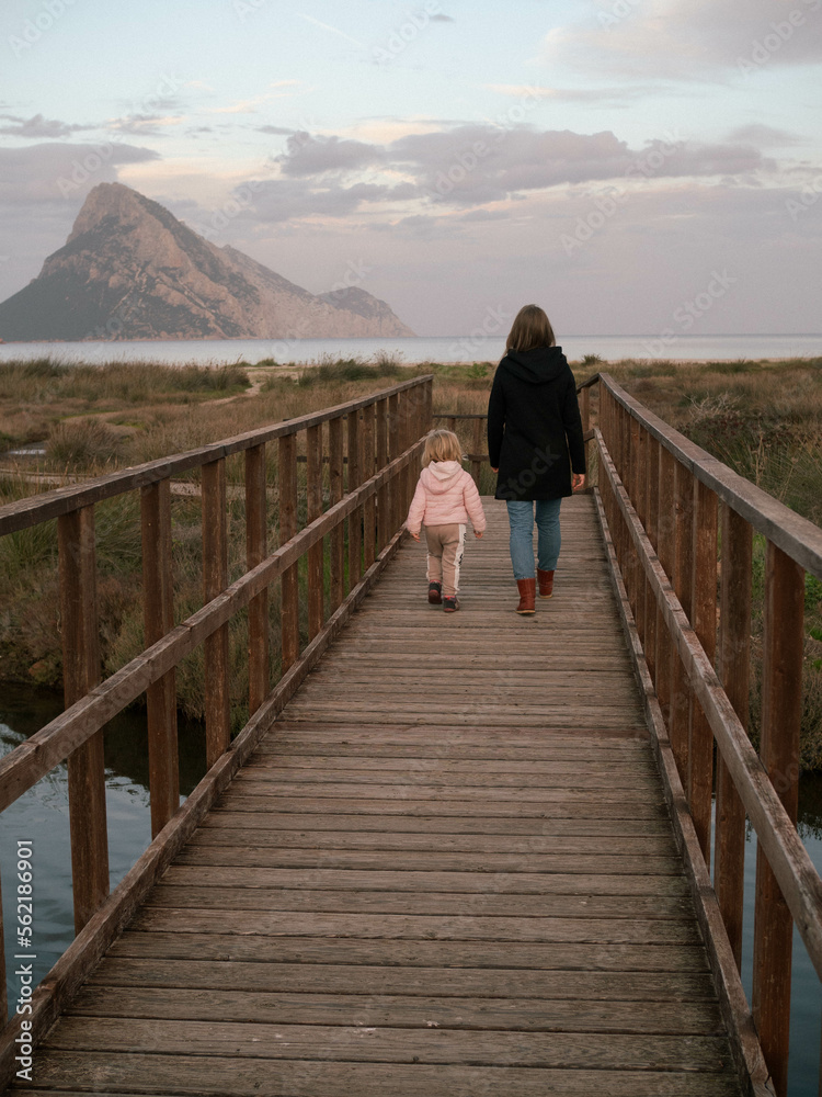 mother and her child walking on the wooden bridge