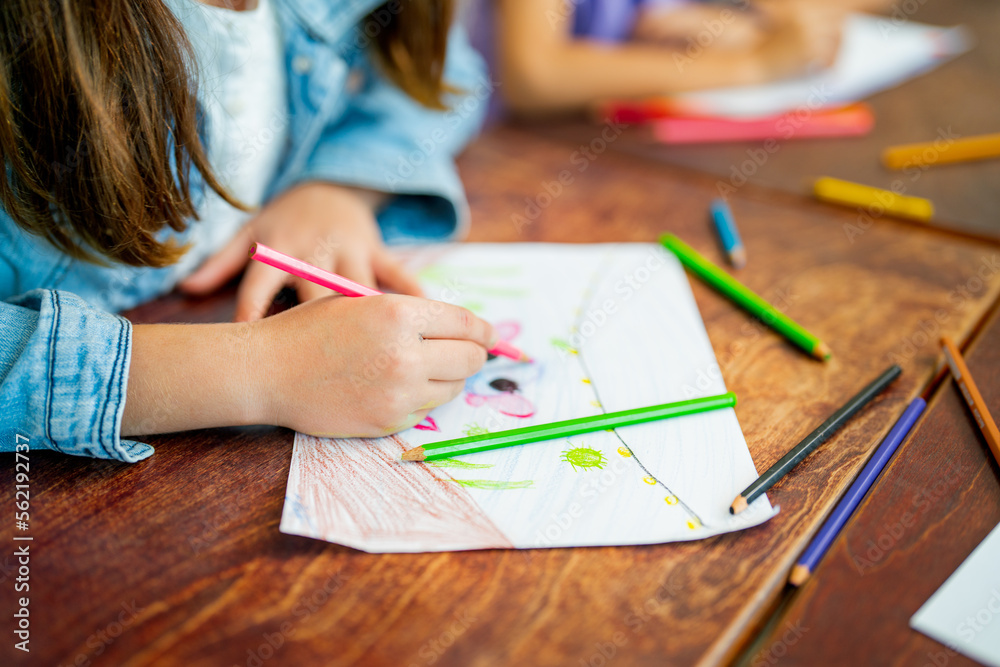Close up hands of little girl draw and paint the picture on paper and sit near her friend in art class at school. Close up hands of little girl draw and paint the picture on paper and sit near her friend in art class at school.
