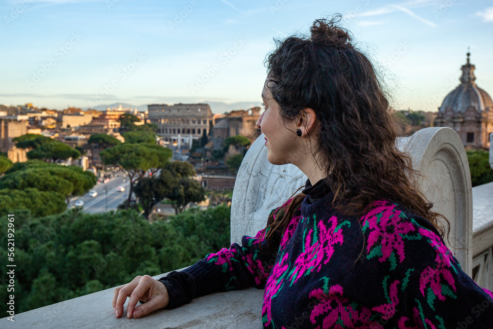 Woman looks at the city, with the view of the Colosseum in the background, in Rome Woman looks at the city, with the view of the Colosseum in the background, in Rome