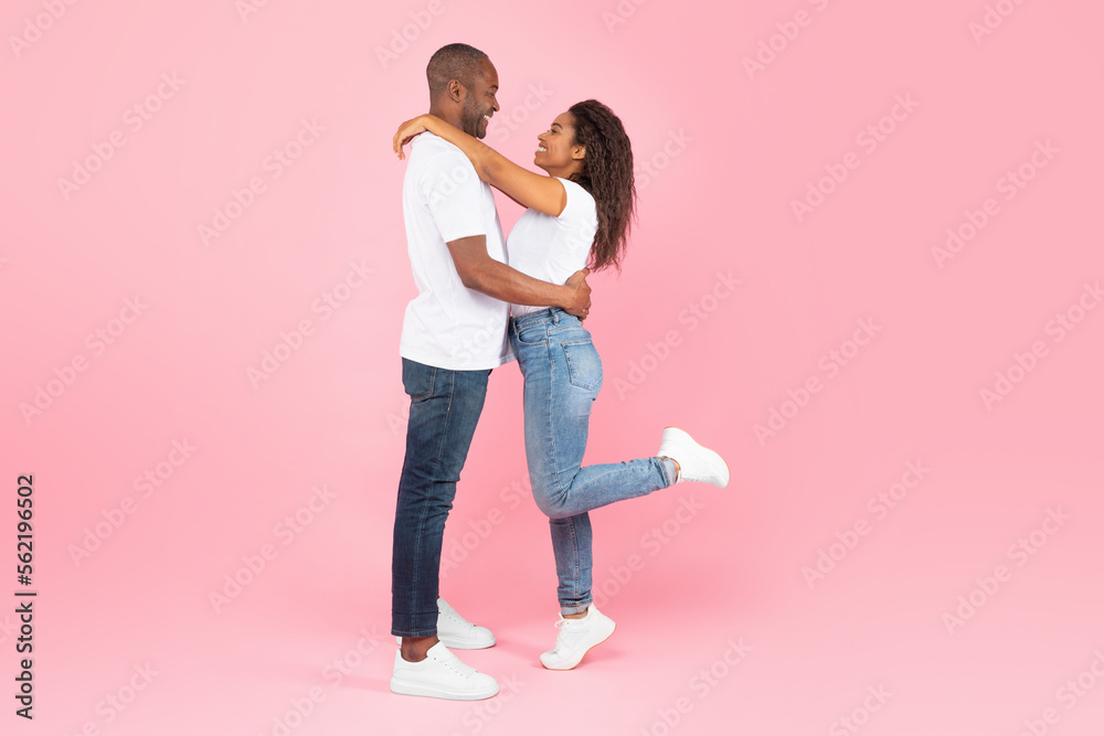 Side view of loving african american couple hugging and looking at each other on pink studio background, copy space Side view of loving african american couple hugging and looking at each other on pink studio background, copy space