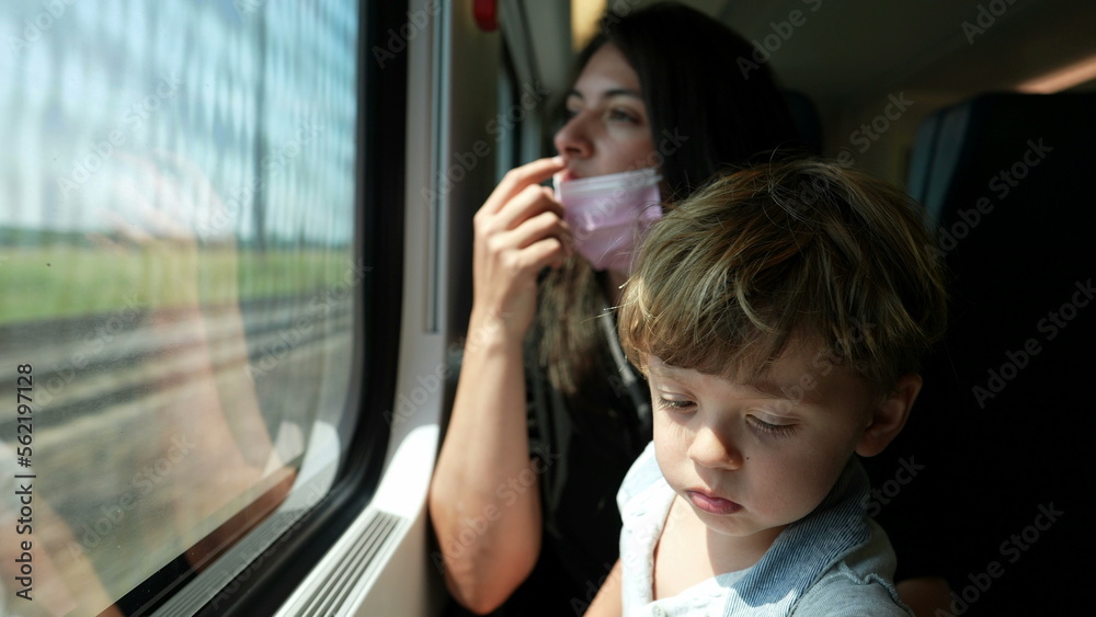 Mother putting surgical face mask while riding ktrain with toddler