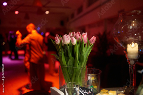 Tulpen im Vordergrund vor unscharf in rotem Licht getauchten Tangotänzern