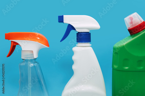 Various spray bottles with detergent on a blue background. The concept of cleaning and disinfection of an office or residential space. Sprayers for cleaning various surfaces