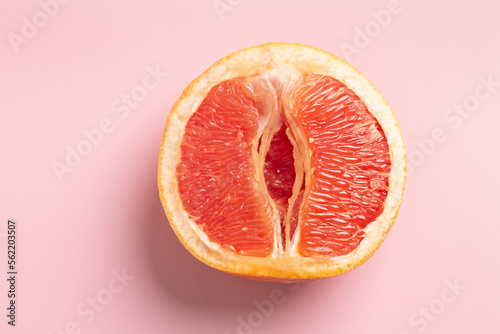 Grapefruit minimal abstract concept. Half a juicy grapefruit close up on a pink background