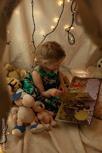 the girl is playing and reading a book in the hut