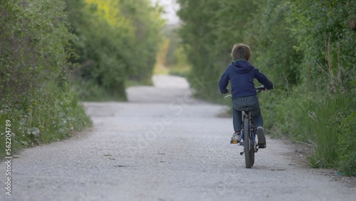 Wallpaper Mural Child riding a bike with back on village road with green trees Torontodigital.ca