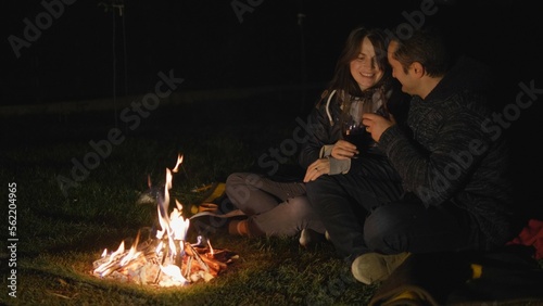 Man and woman with glasses of wine at campfire, romantic night