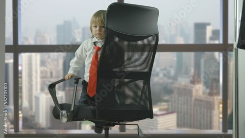 Shy and spoiled child with red tie on businessman armchair, window panorama © MEDIAIMAG