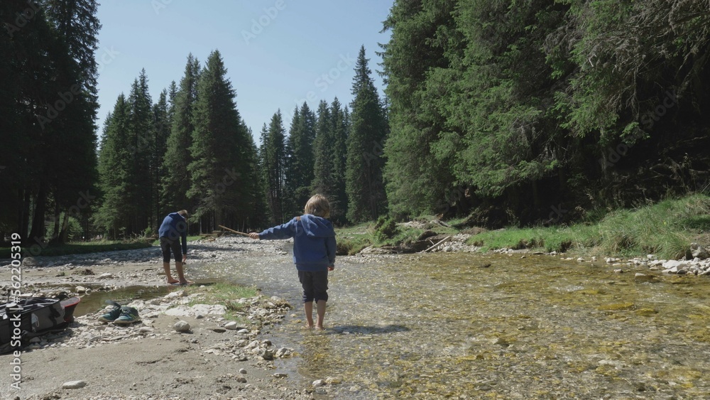 Little child barefoot walking on mountain river, brothers  in nature