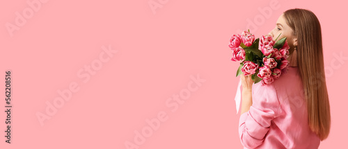 Beautiful woman holding bouquet of flowers on pink background with space for text. International Women's Day #562208516
