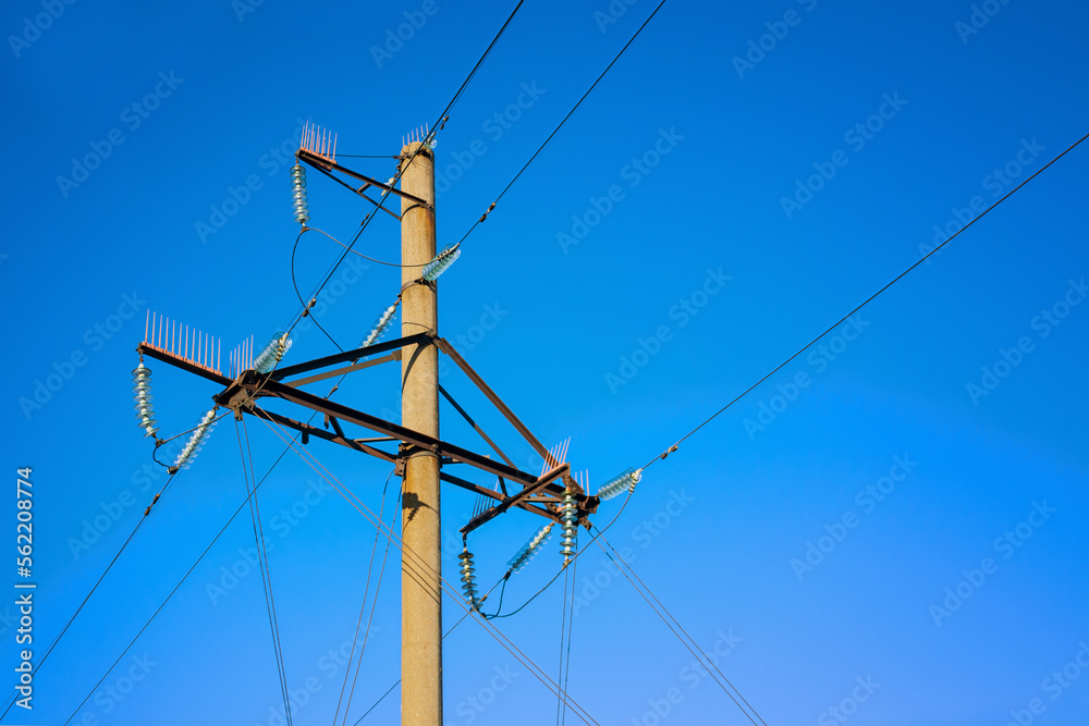 Overhead power line support on the blue sky background.