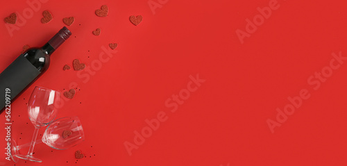 Bottle of wine, glasses and hearts on red background with space for text. Valentine's Day celebration