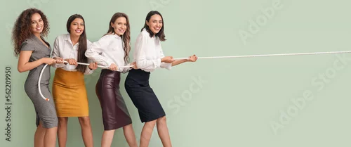 Obraz Young women pulling rope against green wall. Concept of feminism