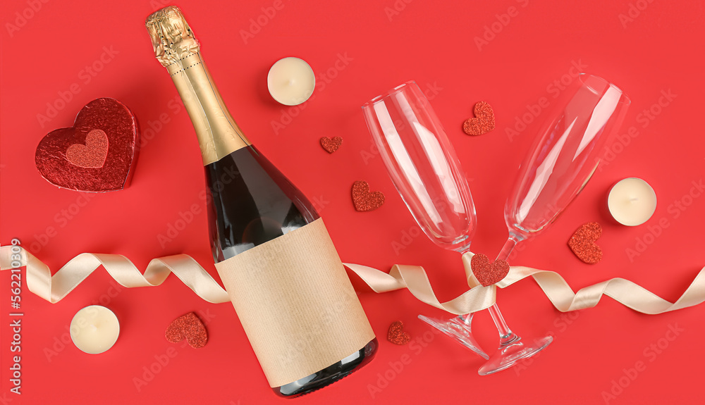 Bottle of champagne, glasses, candles and hearts on red background. Valentine's Day celebration