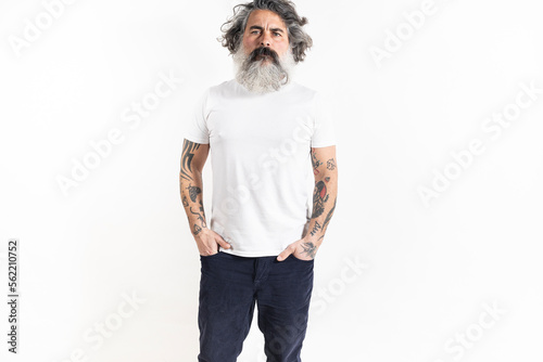 Handsome tattooed bearded man poses in corduroy pants and white premium fine summer t-shirt, isolated on white background