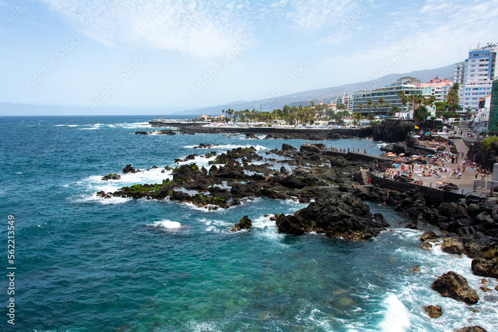 View of the coast and town of Puerto de la Cruz, Tenerife, Spain, with lava stones in the sea