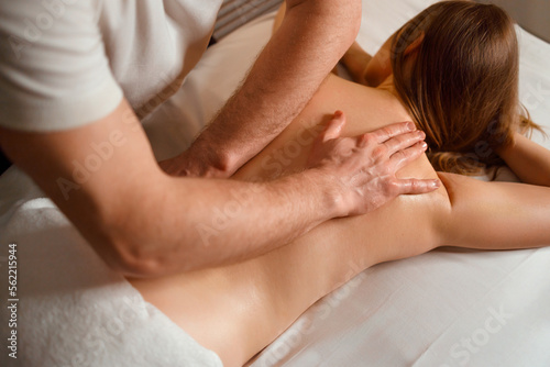 Masseur gives a therapeutic back massage to a young woman