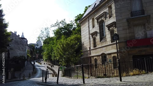 Establishing shot of old street in quarter Montmartre in Paris, France. Cozy cityscape of Paris at summer. Architecture and landmarks of Paris. photo