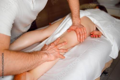 Masseur doing leg massage to woman. Spa treatments
