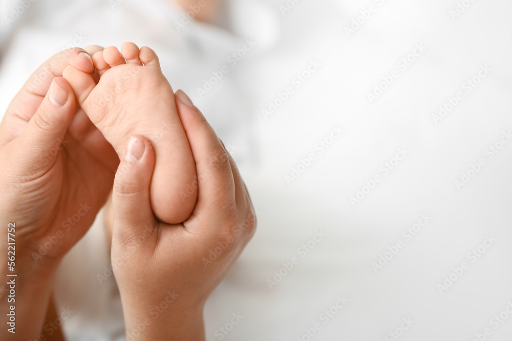Mother massaging her baby's foot in bedroom, closeup Mother massaging her baby's foot in bedroom, closeup