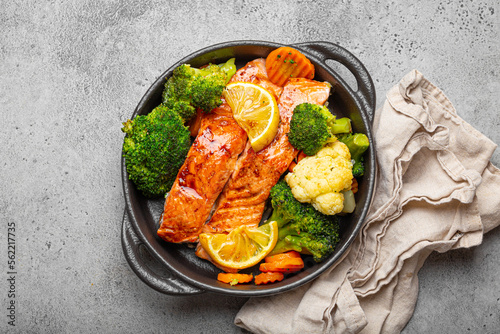 Canvas Print Healthy baked fish salmon steaks, broccoli, cauliflower, carrot in black cast iron casserole bowl on grey rustic stone background