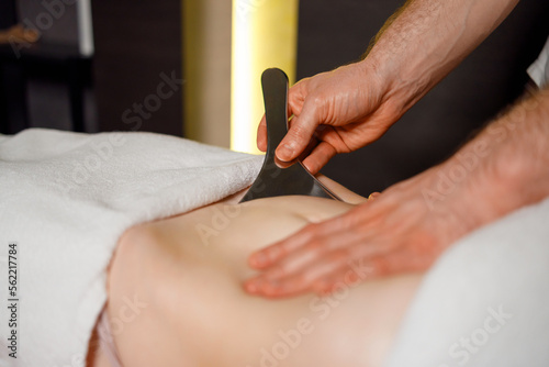 Сlose-up view of the masseur's hands performing a abdominal massage abdominal area using the technique of instrument assisted soft tissue mobilization photo