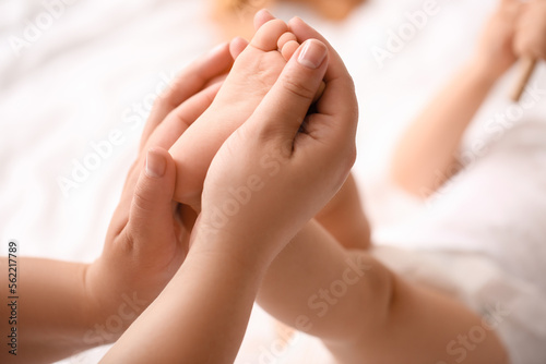 Mother massaging her baby's foot in bedroom, closeup © Pixel-Shot
