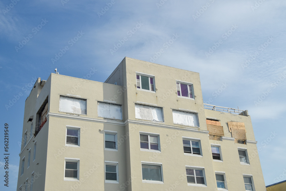 Tall apartment building with the windows near the top removed and the holes covered over