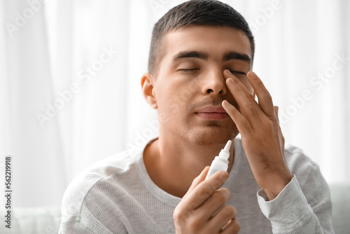 Young man with eye drops at...