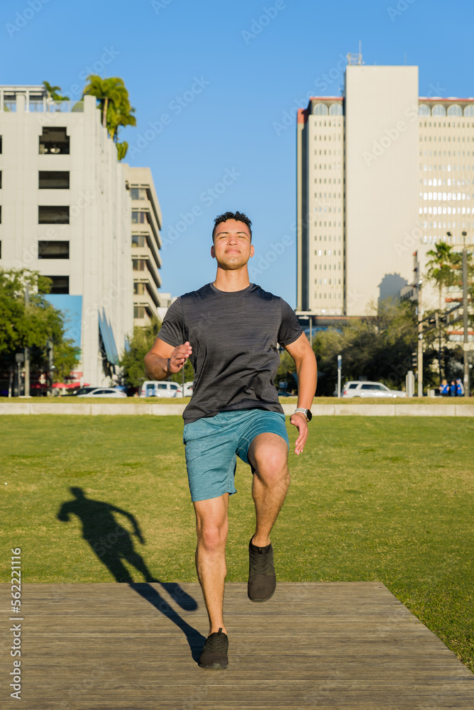 Young athlete does fitness workout in the city park, leg stretching; active urban lifestyle concept