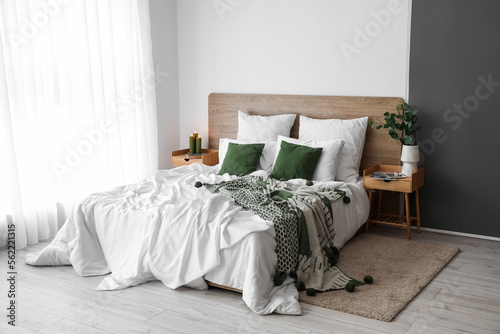 Interior of light bedroom with wooden tables and big bed