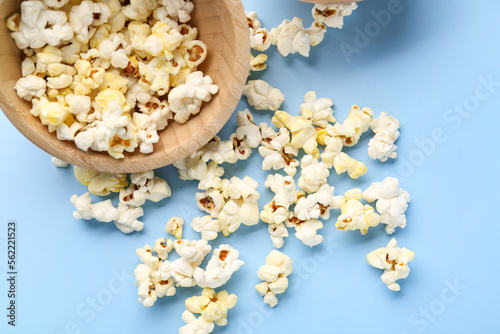 Wooden bowl of tasty popcorn on color background, closeup