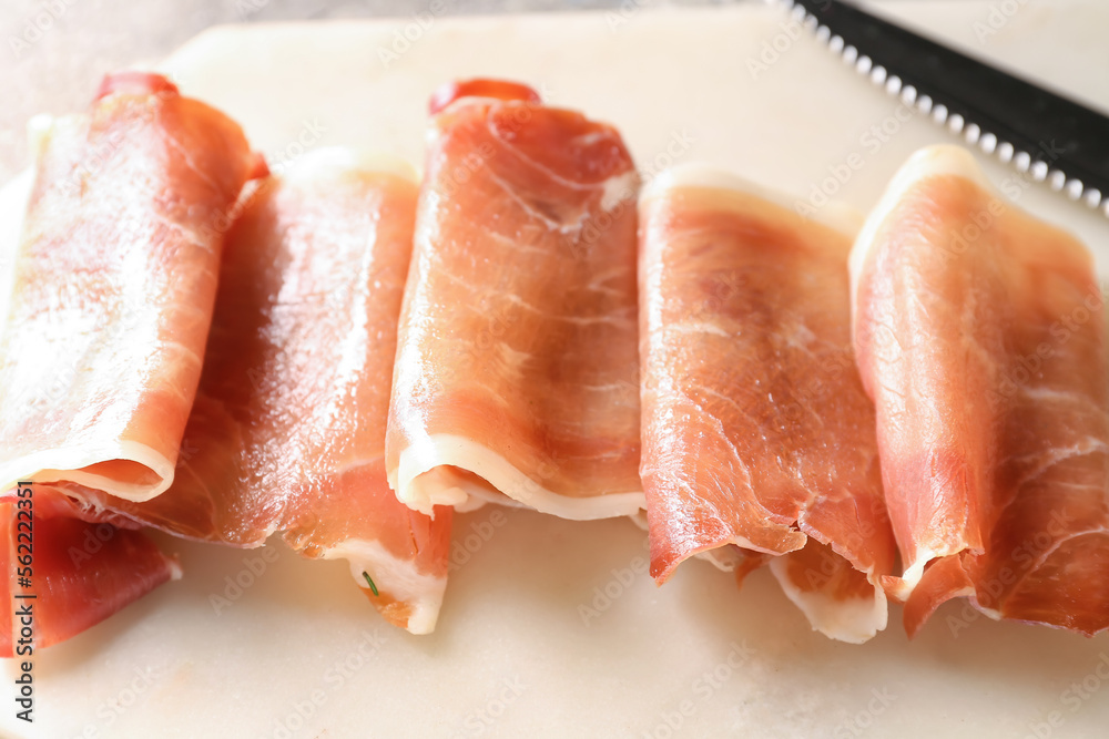 Board with rolled slices of delicious ham, closeup