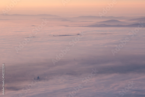 Surreal aerial view of Santa Maria degli Angeli church in Assisi, Italy, above a sea of fog at sunset