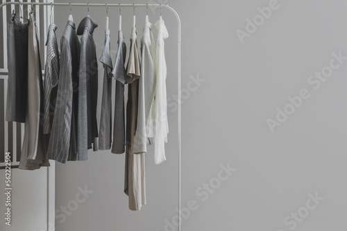 Rack with stylish female clothes and folding screen near grey wall