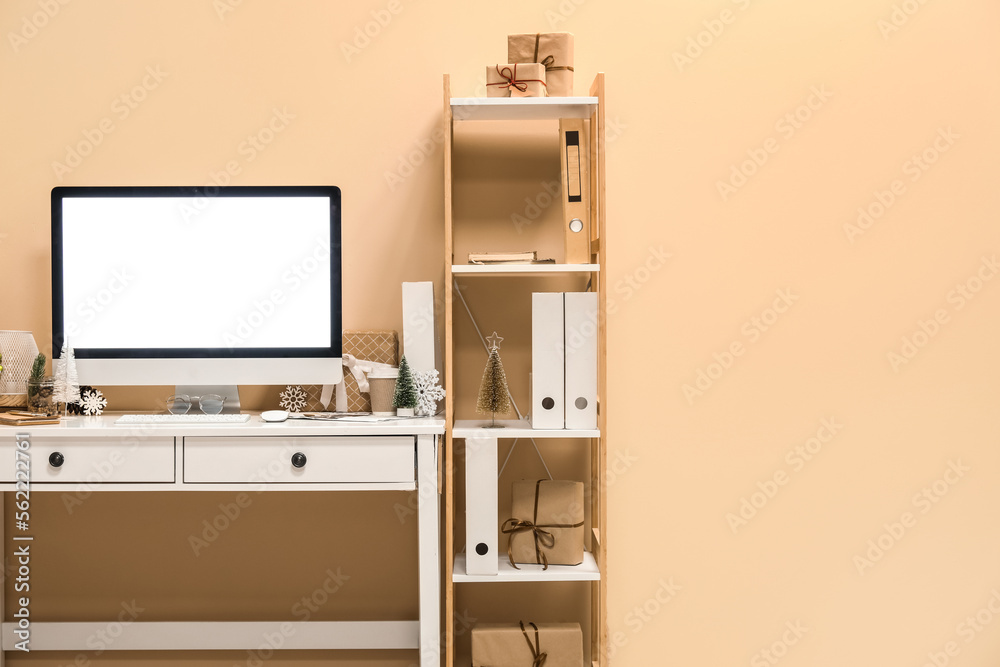 Fototapeta premium Workplace with computer and Christmas decor near beige wall in office