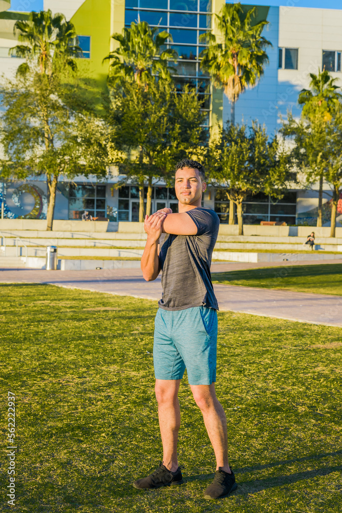 Young muscular man exercising outdoor, in a city park, downtown, stretching hands, healthy urban lifestyle concept. Young muscular man exercising outdoor, in a city park, downtown, stretching hands, healthy urban lifestyle concept.
