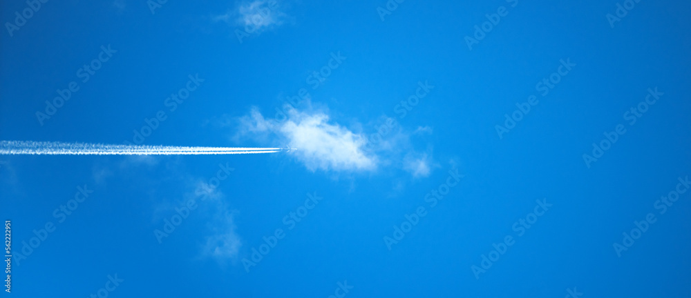 A passenger plane is flying through the blue sky in white clouds. Journey. Vacation. The plane flies through white clouds leaving a white trail. A passenger plane is flying through the blue sky in white clouds. Journey. Vacation. The plane flies through white clouds leaving a white trail.