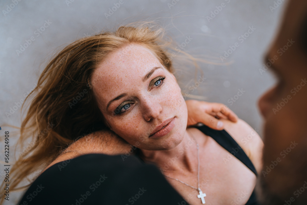 Fototapeta premium Young redhead American young adult woman looks at her man. Close up of man holding girlfriend on hand wants to kiss. Romance. Cropped image of lovers, couple in love. Valentine's day. Relations.