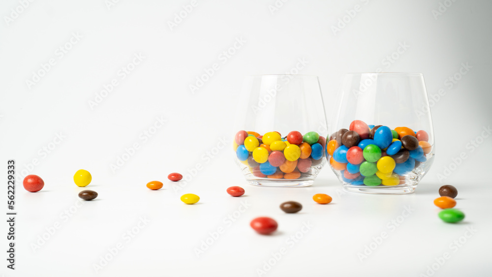 Colorful candy dragee in glasses on white background. Two jars of candies. Candy drink. Kids cocktails Colorful candy dragee in glasses on white background. Two jars of candies. Candy drink. Kids cocktails