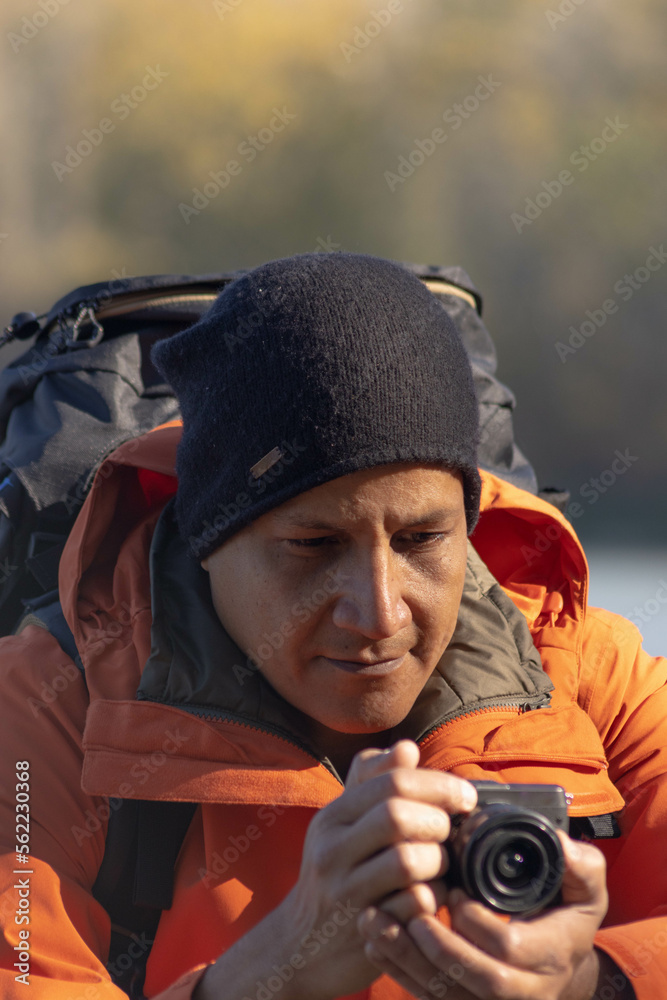 Obraz premium Portrait of traveler man at lake in autumn taking a photo with the digital camera