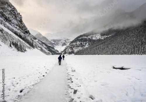 Two unidentifiable people walk across frozen Lake Louise in Banff National Park, Alberta, Canada