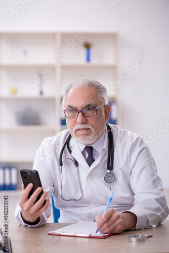 Old male doctor in telemedicine concept