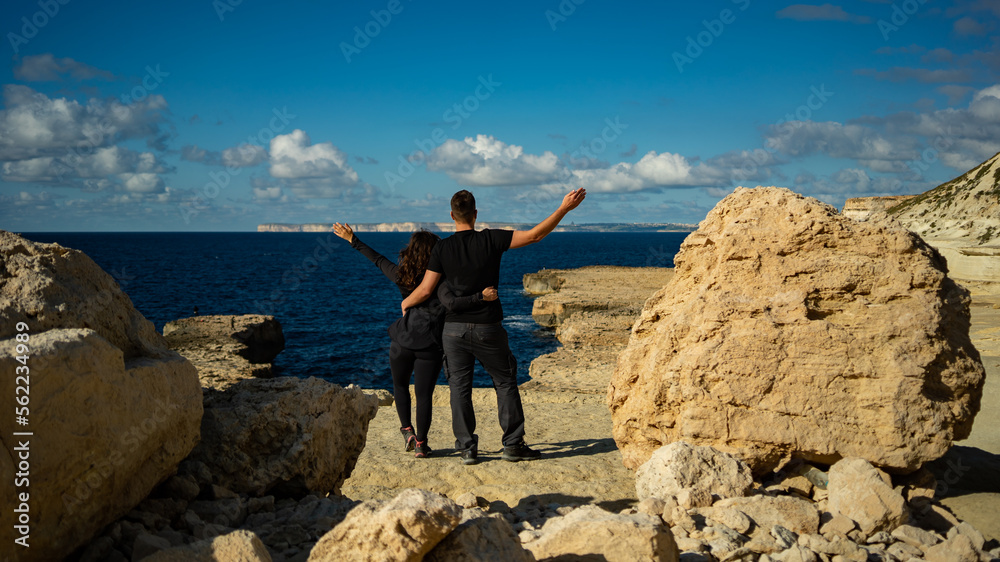 Obraz premium Young happy couple standing on top of the cliff in Malta-Blata tal melħ during vacation 