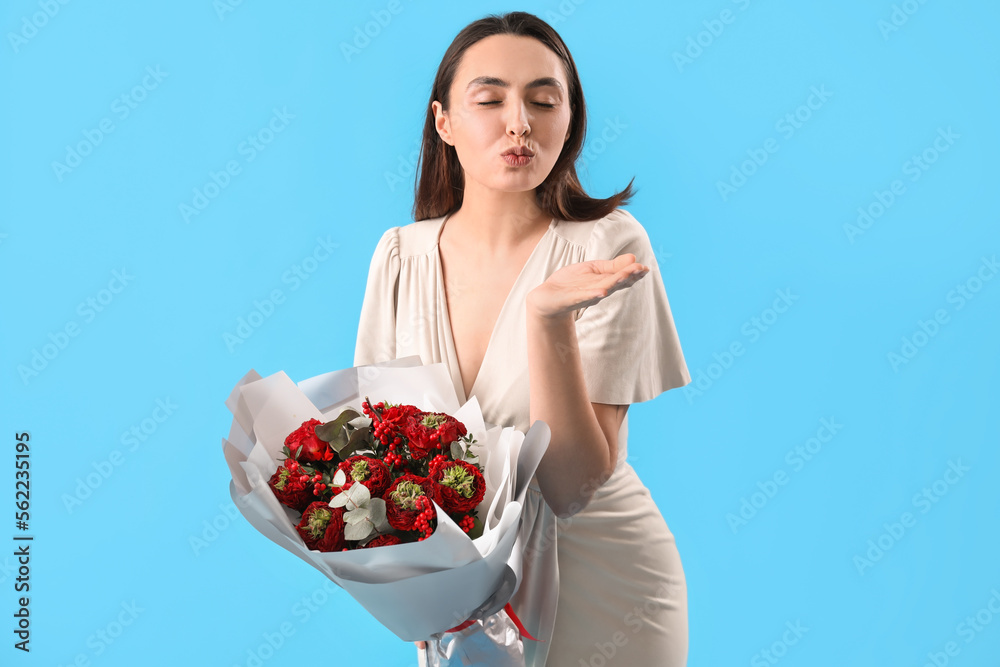 Young woman with bouquet of flowers blowing kiss on blue background. Valentine's Day celebration Young woman with bouquet of flowers blowing kiss on blue background. Valentine's Day celebration