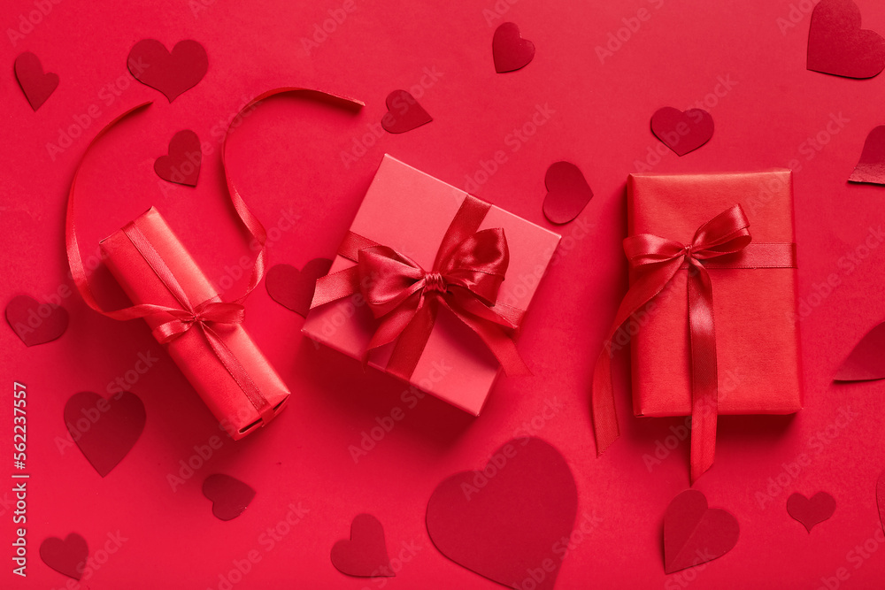Fototapeta premium Gift boxes and paper hearts on red background. Valentine's Day celebration